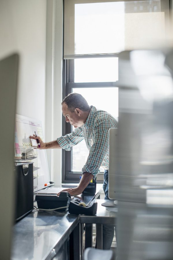 Office life. A man standing up working and making notes on a wall chart. Project management.