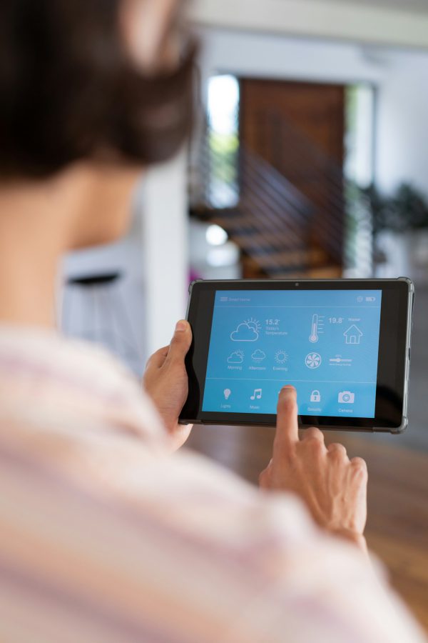 Vertical of hands of biracial man at home using tablet with smart home interface, copy space